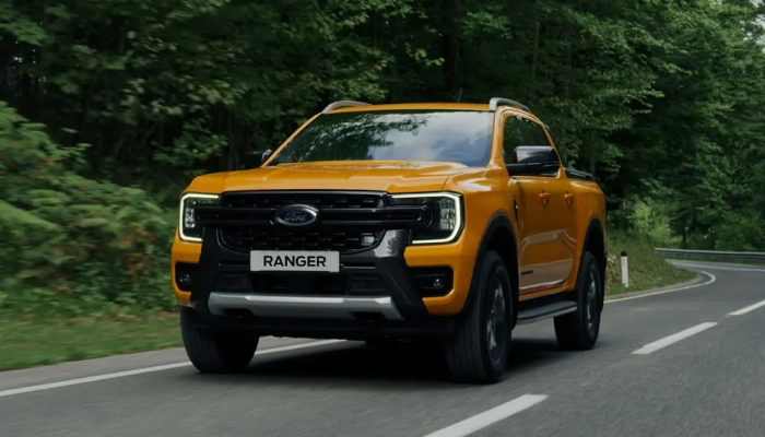 Orman yolunda ilerleyen sarı Ford Ranger