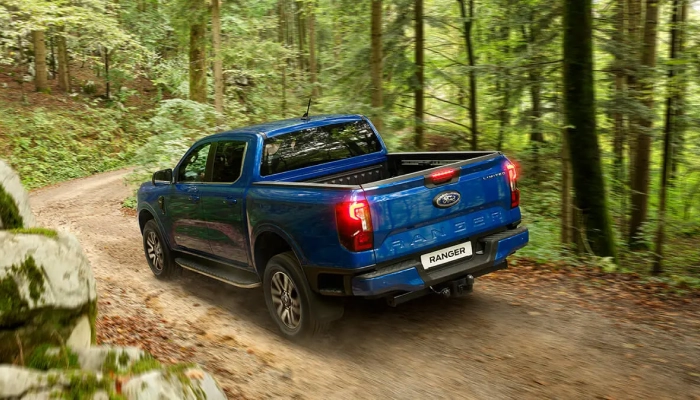 Orman yolunda ilerleyen mavi Ford Ranger'ın arkadan görünümü